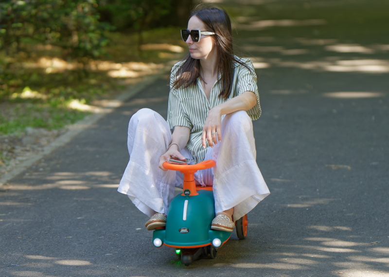 30 - Woman sitting on a green and orange Noriel Aventura musical swing car